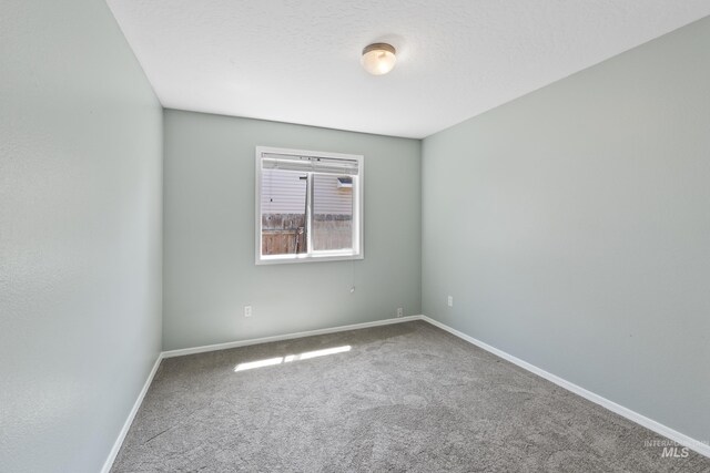 carpeted spare room featuring baseboards