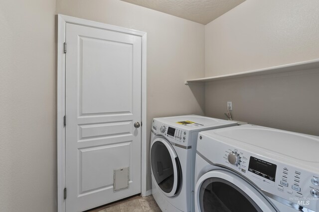 clothes washing area with washer and dryer, a textured ceiling, and laundry area