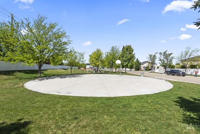 view of home's community featuring a lawn, community basketball court, and fence