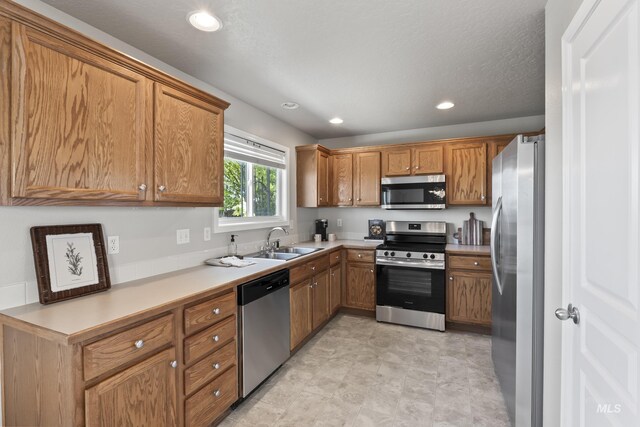 kitchen with stainless steel appliances, recessed lighting, brown cabinetry, and a sink