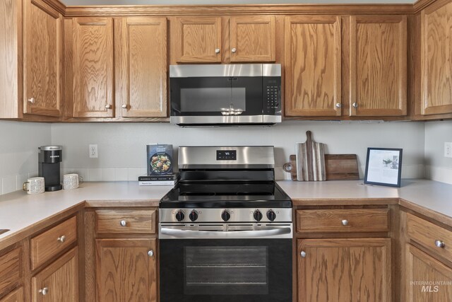 kitchen featuring light countertops, stainless steel appliances, and brown cabinets