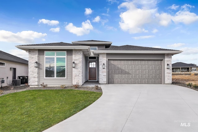 prairie-style house featuring central AC unit, a front lawn, and a garage