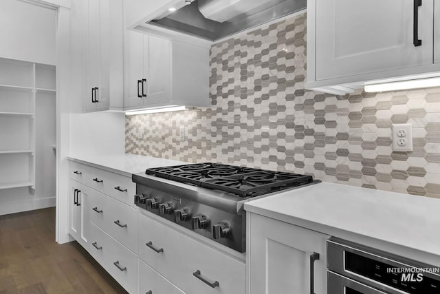 kitchen featuring tasteful backsplash, stainless steel gas cooktop, wall chimney range hood, and white cabinetry