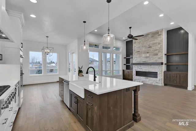 kitchen featuring light hardwood / wood-style floors, sink, white cabinetry, built in features, and a stone fireplace