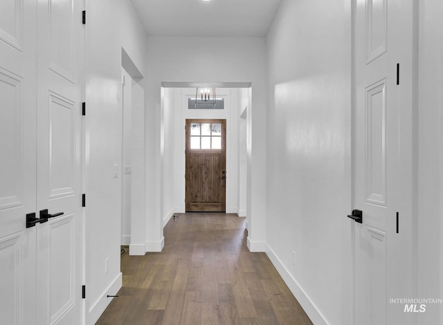 hallway featuring dark hardwood / wood-style flooring and a chandelier