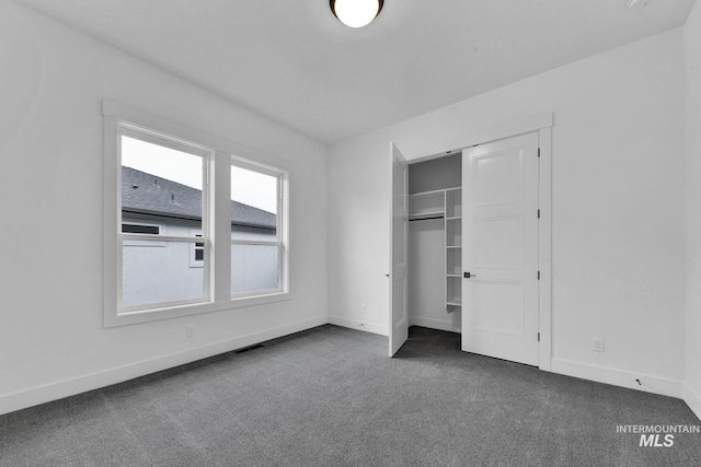 unfurnished bedroom featuring a closet and dark carpet