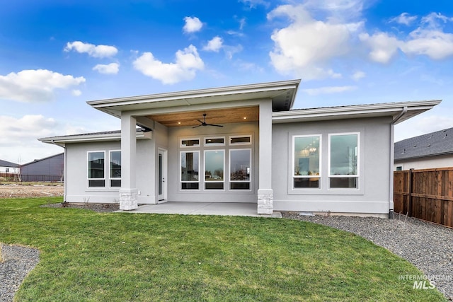 rear view of property featuring ceiling fan, a patio area, and a yard