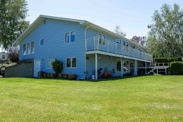 back of property with central AC unit, a balcony, and a yard