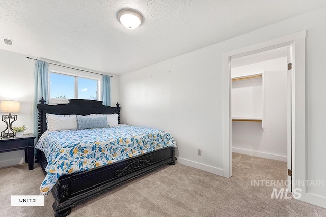 bedroom featuring light carpet and a textured ceiling