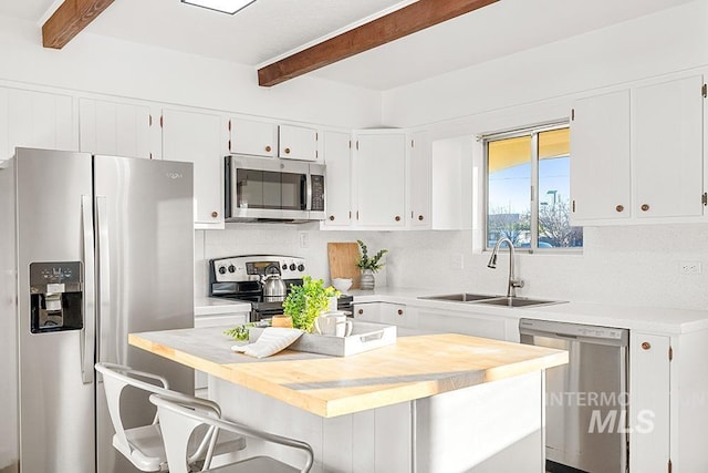 kitchen with sink, beamed ceiling, stainless steel appliances, and white cabinetry