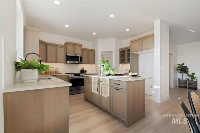 kitchen with stainless steel appliances, sink, light hardwood / wood-style flooring, and backsplash