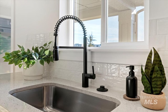 details with light stone countertops, sink, and decorative backsplash