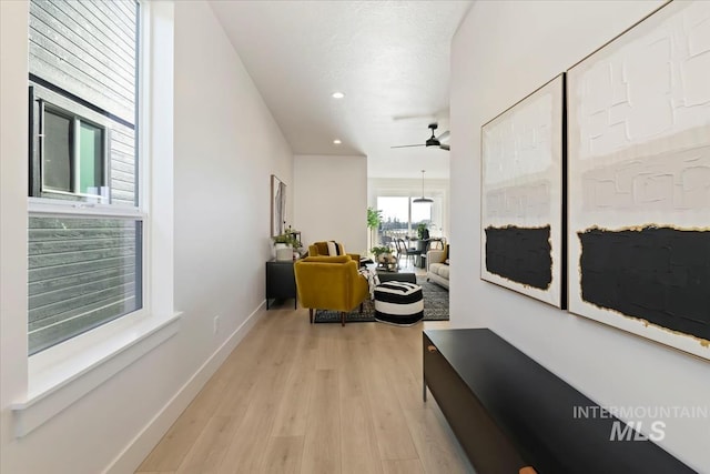 hall with light hardwood / wood-style floors and a textured ceiling