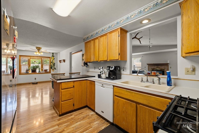 4667 S Shawnee Way, Boise, ID 83709 - kitchen with white dishwasher, a peninsula, black gas range, healthy amount of natural light, and a textured ceiling