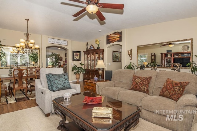 living area featuring ceiling fan, arched walkways, a chandelier, wood finished floors, and lofted ceiling