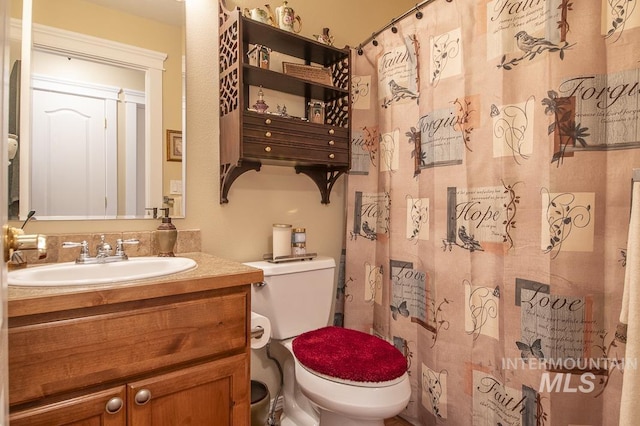 bathroom featuring toilet, vanity, and a shower with curtain