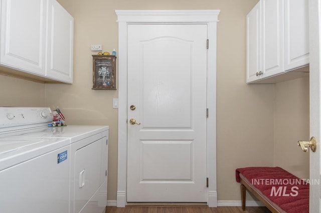 laundry area with separate washer and dryer, cabinet space, baseboards, and wood finished floors
