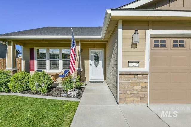 view of exterior entry featuring a porch, roof with shingles, and an attached garage