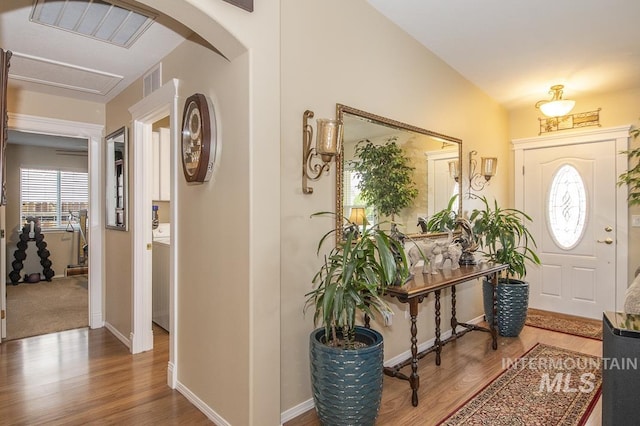 foyer with wood finished floors, baseboards, and arched walkways