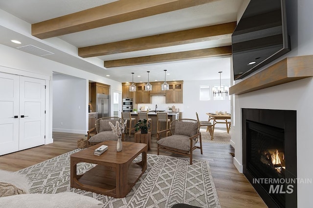 3389 E Englehart Dr, Meridian, ID 83642 - living area with wood finished floors, beam ceiling, a chandelier, a glass covered fireplace, and recessed lighting
