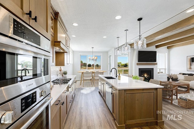 3389 E Englehart Dr, Meridian, ID 83642 - kitchen featuring stainless steel appliances, recessed lighting, open floor plan, light countertops, and a warm lit fireplace