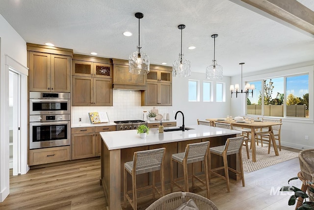 3389 E Englehart Dr, Meridian, ID 83642 - kitchen featuring light wood-type flooring, decorative backsplash, a kitchen island with sink, light countertops, and stainless steel appliances