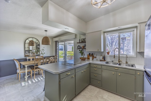 kitchen with white electric cooktop, light countertops, decorative backsplash, a peninsula, and a sink