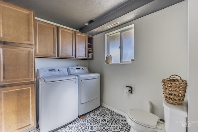 clothes washing area featuring visible vents, washer and dryer, a textured ceiling, baseboards, and laundry area