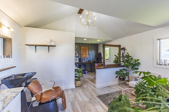 living room featuring an inviting chandelier, vaulted ceiling, and light wood finished floors