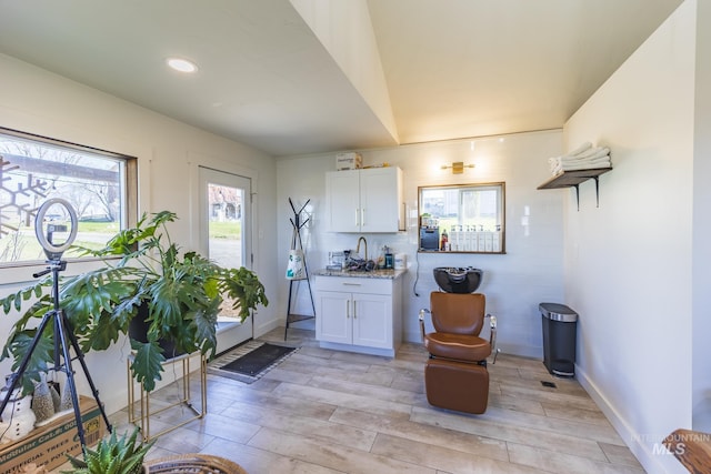 interior space with light wood finished floors, white cabinets, baseboards, and light stone countertops