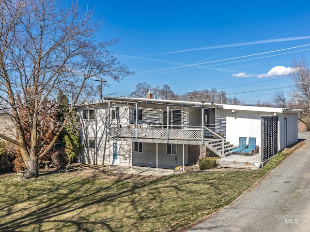 rear view of property featuring a lawn and a deck