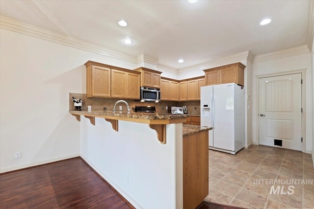 kitchen featuring sink, backsplash, ornamental molding, white fridge with ice dispenser, and kitchen peninsula