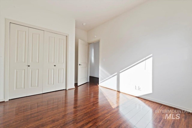 unfurnished bedroom with dark wood-type flooring and a closet