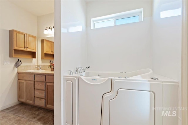 bathroom featuring vanity, washer / clothes dryer, and a bathtub