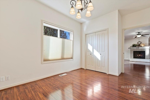 foyer with hardwood / wood-style flooring, a fireplace, and ceiling fan with notable chandelier