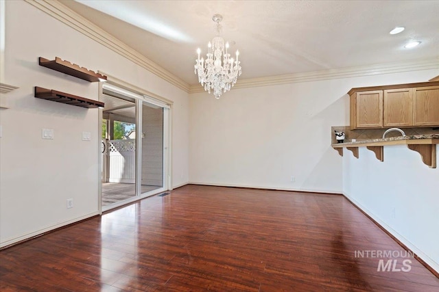 unfurnished dining area with a notable chandelier, dark wood-type flooring, and ornamental molding