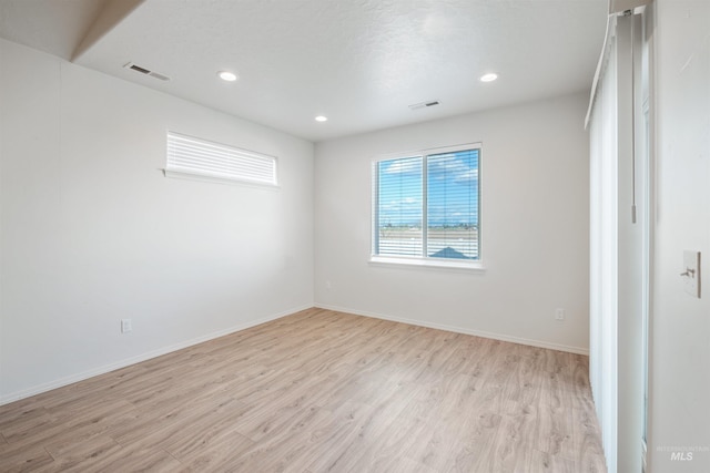 empty room featuring baseboards, visible vents, light wood-style floors, and recessed lighting