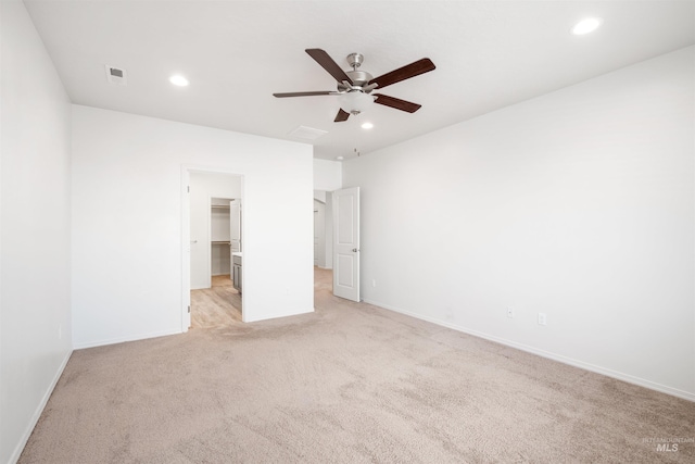 unfurnished bedroom with visible vents, baseboards, recessed lighting, a walk in closet, and light colored carpet