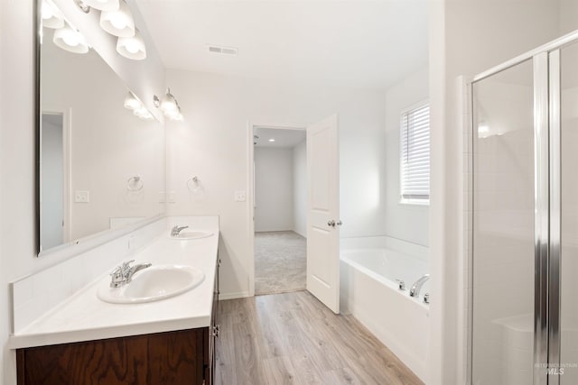 bathroom featuring a sink, a garden tub, a shower stall, and wood finished floors