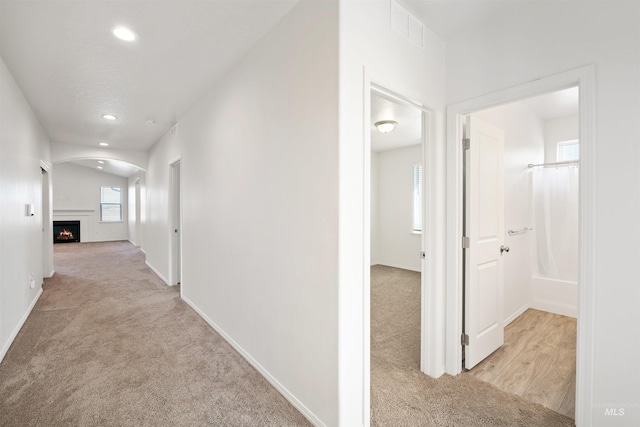 corridor featuring carpet flooring, visible vents, baseboards, recessed lighting, and arched walkways