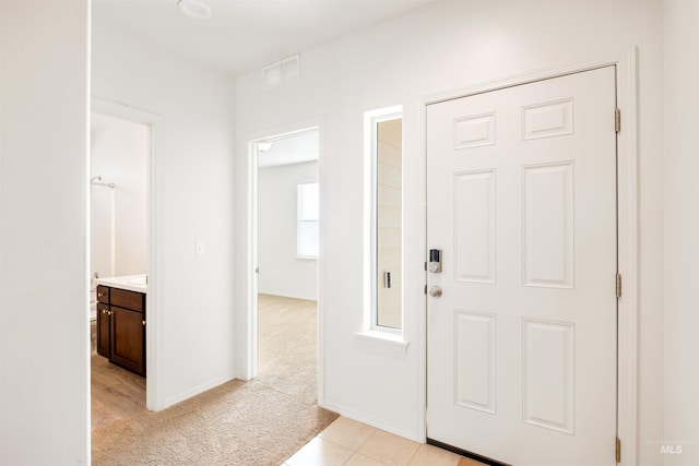 entryway with baseboards, light colored carpet, and visible vents