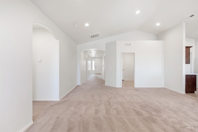 unfurnished living room featuring arched walkways, lofted ceiling, and visible vents
