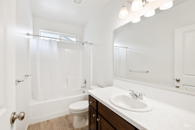 full bath featuring toilet, vanity, wood finished floors, shower / tub combo, and visible vents