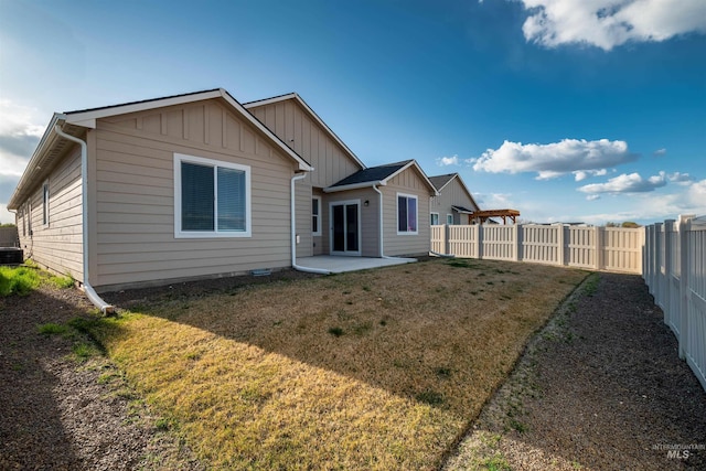 rear view of house featuring a fenced backyard, a patio area, board and batten siding, and a yard