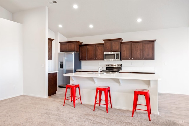 kitchen featuring light countertops, recessed lighting, a sink, a large island, and appliances with stainless steel finishes