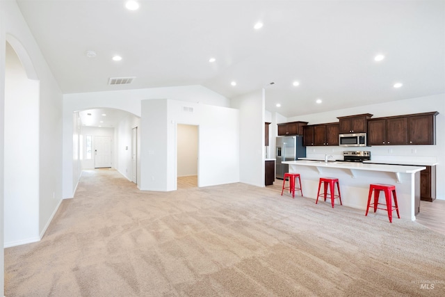 kitchen featuring light countertops, a spacious island, arched walkways, visible vents, and appliances with stainless steel finishes