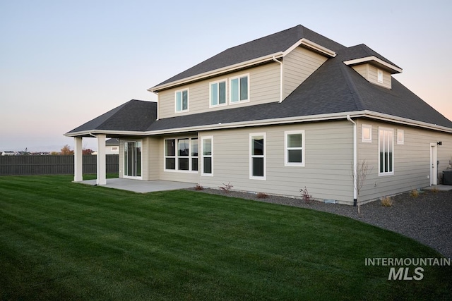 back house at dusk with a patio area and a yard