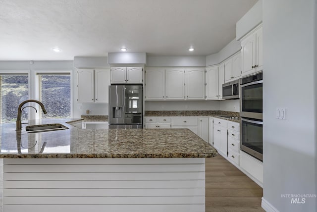 816 River View Dr, Twin Falls, ID 83301 - kitchen with stainless steel appliances, dark stone countertops, a sink, light wood-type flooring, and white cabinetry