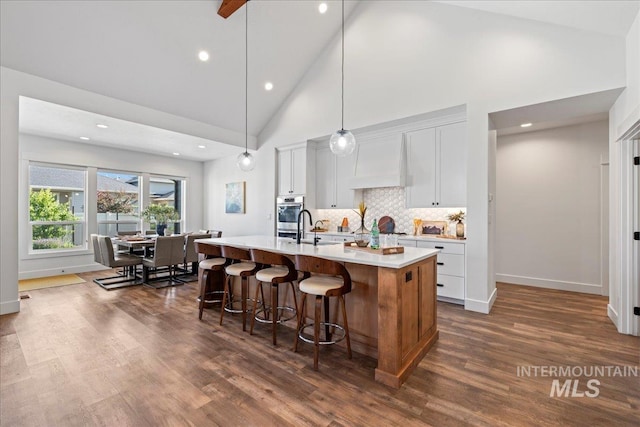492 Applecreek St, Middleton, ID 83644 - kitchen with custom range hood, an island with sink, light countertops, dark wood-style flooring, and white cabinetry