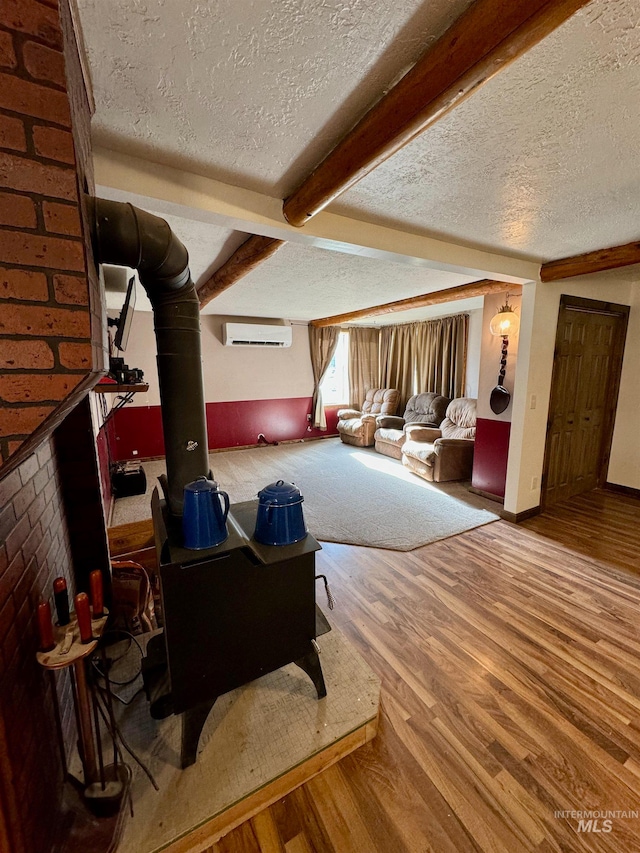 living room with wood-type flooring, a textured ceiling, beam ceiling, and a wall mounted AC